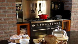 A kitchen with a brick archway, a stove, and a table with bread and tea cups. - Large Luxury House in Excellent Location. Ideal for families  (Killarney)