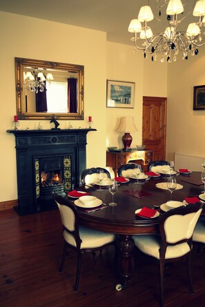 Comedor con chimenea, candelabro y mesa dispuesta para seis comensales.