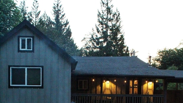 Ein Lagerfeuer mit Holzscheiten, ein Haus mit Veranda und eine Holzterrasse.
