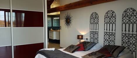 A bedroom with a bed, a nightstand, a lamp, and decorative wall art.