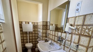 Un baño con inodoro, lavamanos y espejo. Hay una toalla en el suelo y una alfombra pequeña.