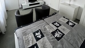 Habitación de hotel moderna con una cama, un escritorio, una silla, un televisor, un espejo y un cuadro en la pared.