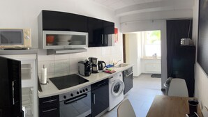 Una cocina compacta equipada con microondas, estufa, lavamanos y lavadora.