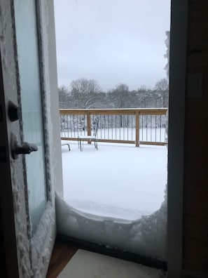 A view from a room with a door leading to a balcony. The balcony has a wooden railing and is covered with snow. - Wilderness Country Inn: Canada (Mentone)
