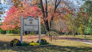 A sign welcoming visitors to The Wilderness of Mentor, established in 2004, surrounded by autumn foliage. - Wilderness Country Inn: Canada (Mentone)