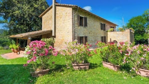 A stone house with a covered porch and potted flowers in the yard. - Poggio al Colle by Interhome (Montaione)