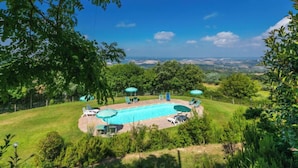 A swimming pool with lounge chairs and umbrellas, surrounded by lush greenery and a scenic view. - Poggio al Colle by Interhome (Montaione)