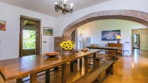 A spacious dining area with a long wooden table, benches, a chandelier, and an arched brick wall. - Poggio al Colle by Interhome (Montaione)