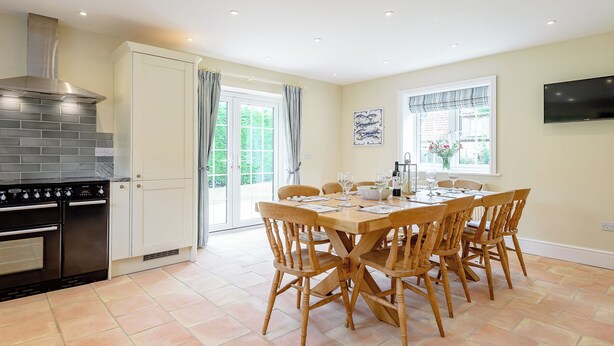 A kitchen with a stove, oven, and a dining area with a table and chairs. - Sea Holly Cottage-UK11931 (Thornham, near Kings Lynn)