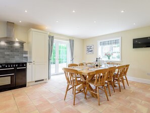 A kitchen with a stove, oven, and a dining area with a table and chairs. - Sea Holly Cottage-UK11931 (Thornham, near Kings Lynn)
