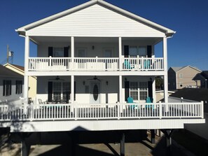 A two-story building with balconies, a covered front porch, and a deck.
