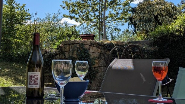 A table with a wine bottle, glasses, and a chair under a canopy. - Gite aux Portes du Morvan, 10 minutes from Vézelay (Nuars)