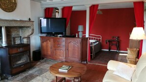 A living room with a television, wooden cabinet, sofa, and a red wall. - Gite aux Portes du Morvan, 10 minutes from Vézelay (Nuars)