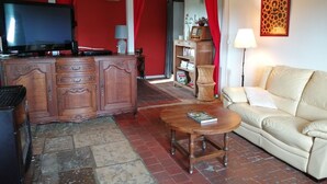 A living room with a sofa, a wooden cabinet, a television, and a bookshelf. - Gite aux Portes du Morvan, 10 minutes from Vézelay (Nuars)