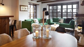 Un salon chaleureux avec une table en bois, un canapé vert et une cheminée.