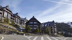 Il s’agit d’un bâtiment de style chalet traditionnel, doté de nombreux balcons et d’un toit à forte pente, situé sur une colline, sous un ciel dégagé.