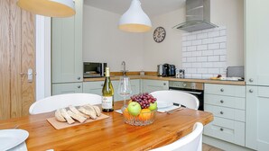 A modern kitchen with white cabinets, a wooden countertop, and a dining area with a white table and chairs. - 1 bedroom accommodation in Roughton, near Woodhall Spa (Roughton, near Woodhall Spa)