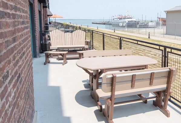 A patio with wooden furniture, a brick wall, and a view of the water and dock.