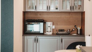 Een compacte keuken met een ingebouwde oven, een koffiezetapparaat en een spoelbak.