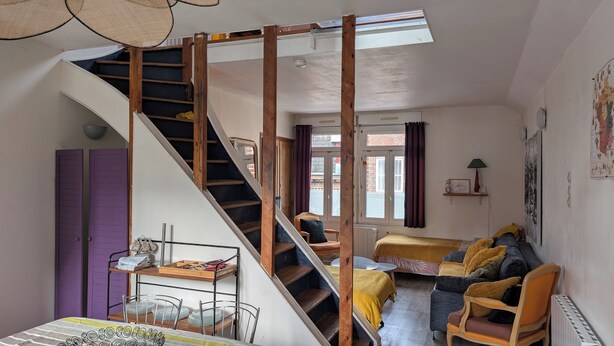 A room with a staircase, a bed, a sofa, and a dining area. - Bright Duplex in Lille-Wazemmès (Lille)