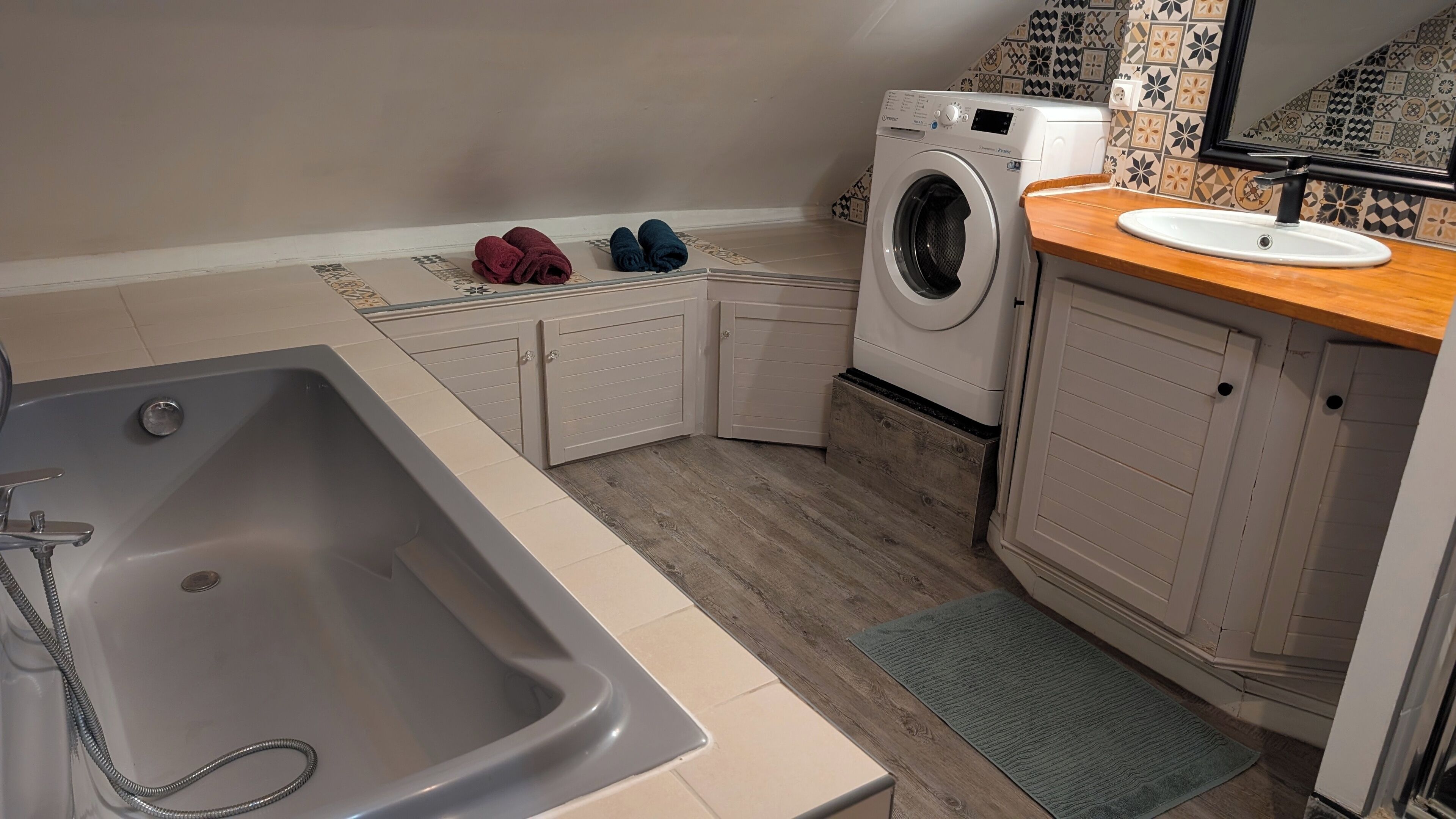A compact kitchen with a built-in washing machine, a sink, and wooden cabinets.