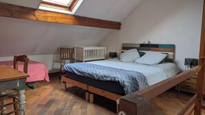 A bedroom with a sloped ceiling, a wooden bed frame, a small desk, and a chair. - Bright Duplex in Lille-Wazemmès (Lille)