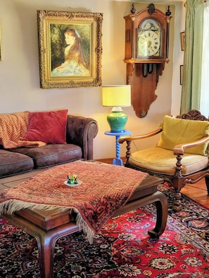 A living room with a sofa, armchair, a table with a lamp, a clock, and a framed picture on the wall. - Spacious apartment In Rolling Hills, Close To The Atlantic Ocean   (Cartes)