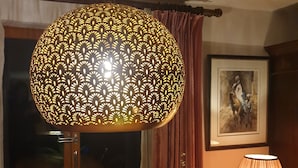 A table with a decorative lamp, a potted plant, and a framed artwork on the wall.