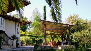 A house with a covered patio, a lawn, and a dog.
