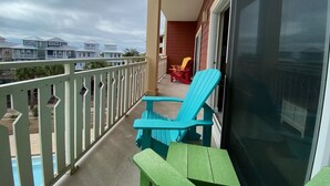 A balcony with a view of other buildings, a sliding glass door, and two chairs. - Cozy Coastal Condo – Walk to Beach, Dine, & Relax! (Mexico Beach)
