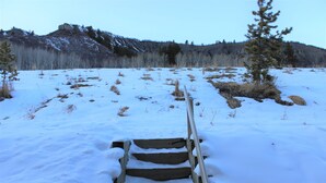 Un escalier en bois menant à une pente enneigée, avec une montagne en arrière-plan.