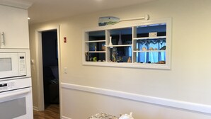 Cocina con encimera de granito, estufa a gas, microondas y ventana con repisas superiores.