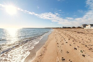 Ein Strand mit Fußspuren, einem Haus und einem klaren Himmel.