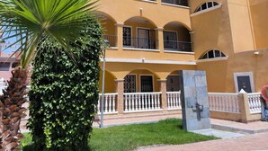 A multi-story hotel with balconies, a swimming pool, and palm trees. -  Wonderful Top Floor Terrace, Distant seaview, Aircon, Free wifi, English TV (Villamartin)