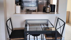 A compact kitchen with white cabinets, a stainless steel refrigerator, a coffee maker, and a small dining table with four chairs. -  Wonderful Top Floor Terrace, Distant seaview, Aircon, Free wifi, English TV (Villamartin)