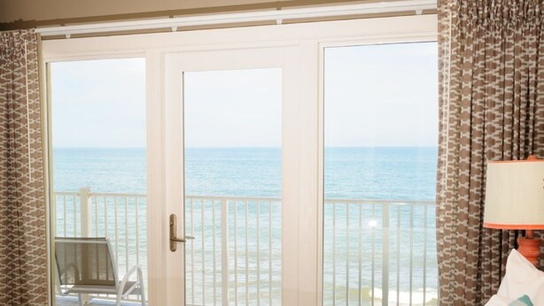 Habitación de hotel con cama, una silla y balcón con vista al mar.