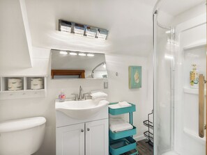 Een badkamer met een witte wastafel, een spiegel, een toilet en een douchehoek.