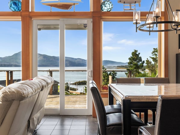 Quarto moderno com porta de vidro deslizante para um deck com vista para um lago e montanhas.