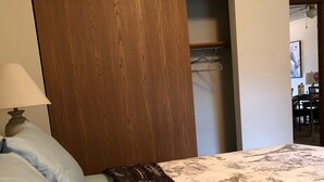 A bedroom with a bed, a wooden wardrobe, and a desk with a chair.