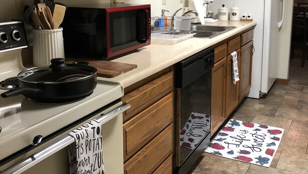 A kitchen with wooden cabinets, a stove, a microwave, a sink, and a refrigerator.