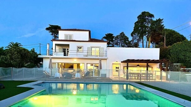 Una casa moderna de dos pisos con una piscina al frente.