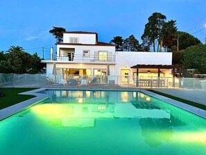 Uma casa moderna de dois andares com piscina em primeiro plano.