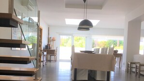 Amplia sala de estar con una escalera, una mesa de comedor y un conjunto de sofás.