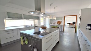 Una cocina moderna con armarios blancos, una isla central e iluminación colgante.