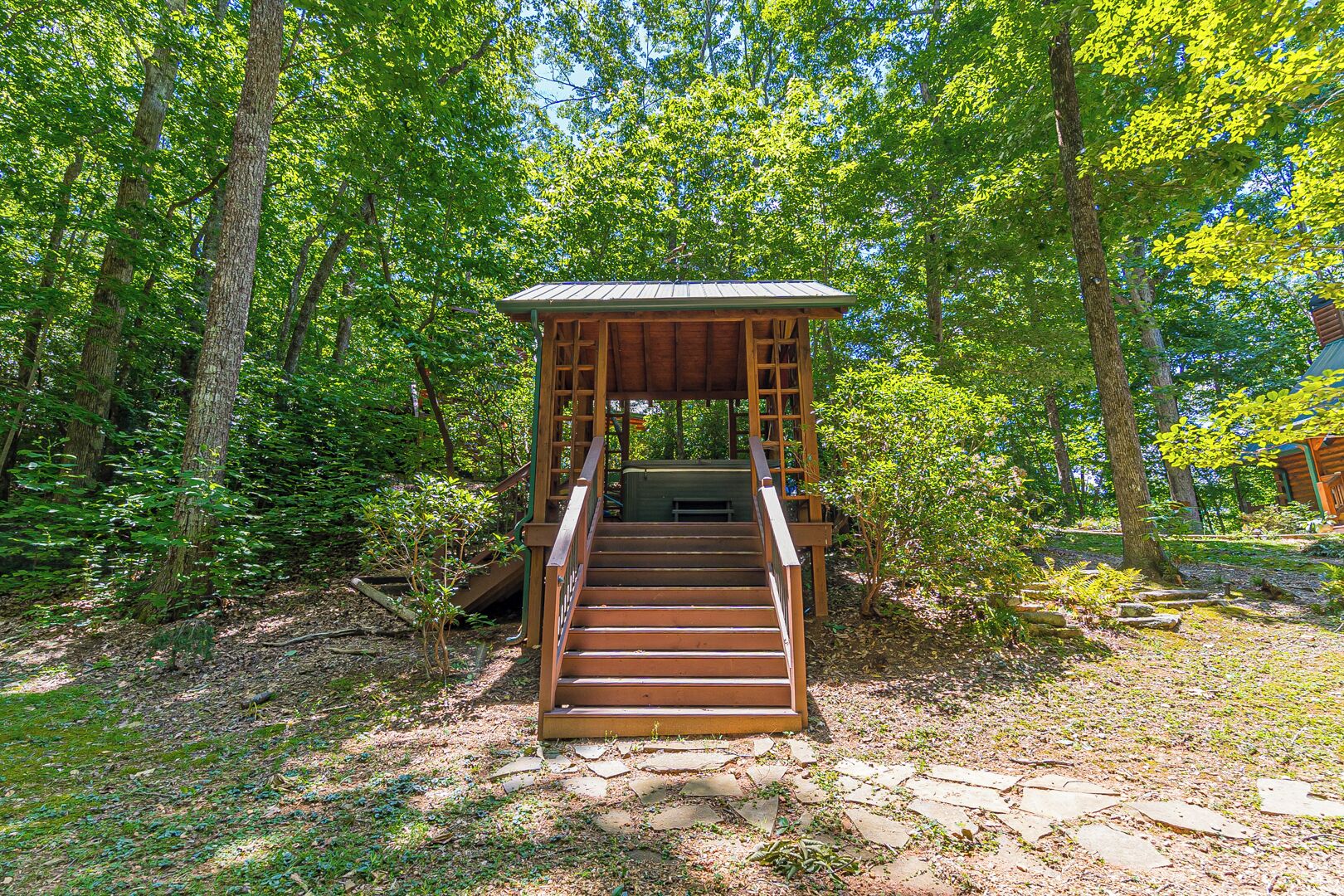 A wooden staircase leading to a covered wooden structure in a forested area.