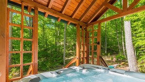 A hot tub in a wooden gazebo surrounded by a forest.