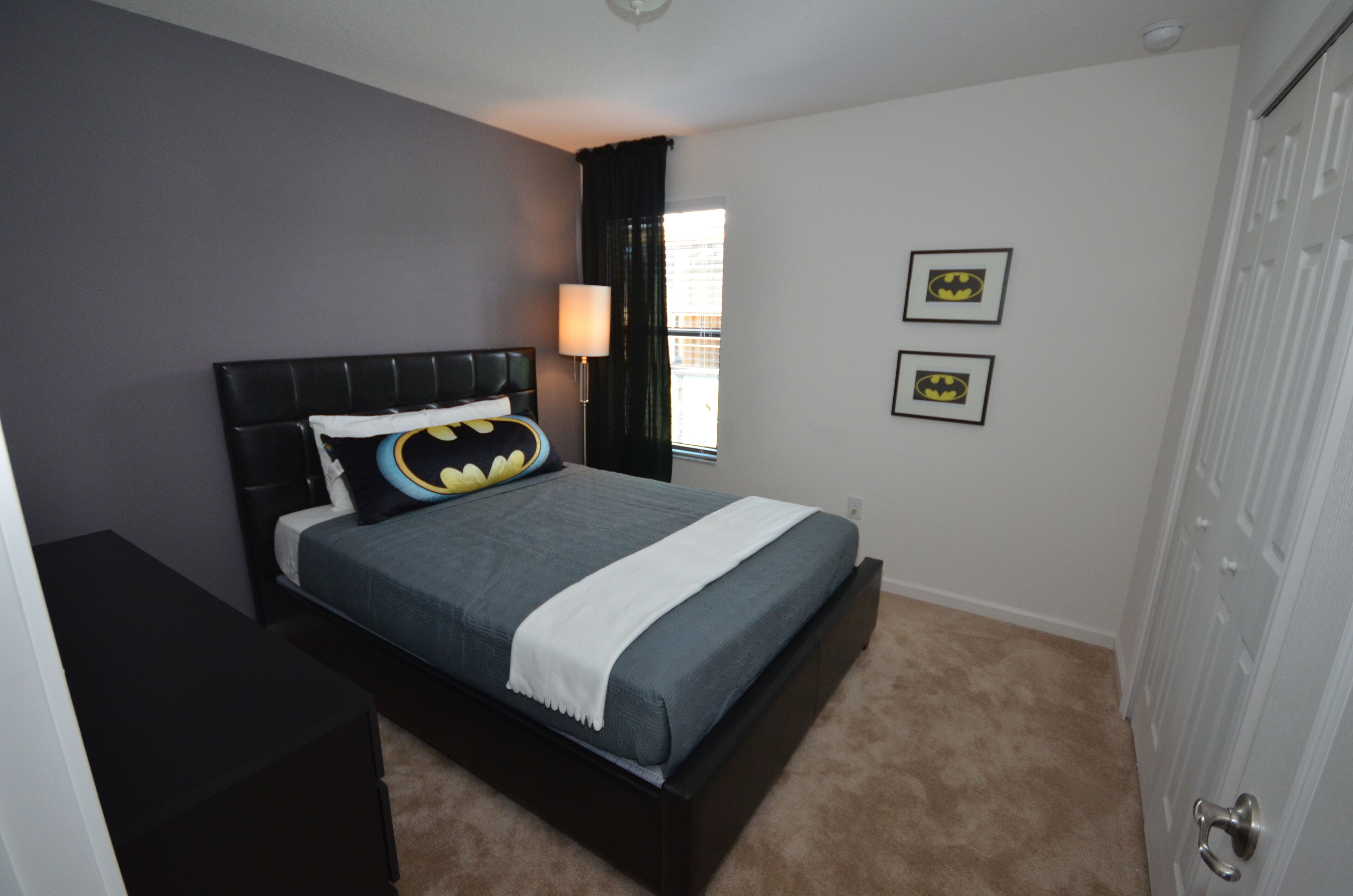 A bedroom with a bed, a nightstand, a lamp, and two framed pictures on the wall.