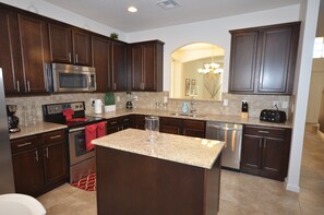 A modern kitchen with dark wood cabinets, stainless steel appliances, and a granite countertop.