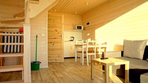 A compact wooden cabin with a dining area, a kitchenette, and a sofa. - Cottages for families with children or guests who want to relax. (Sarbinowo)
