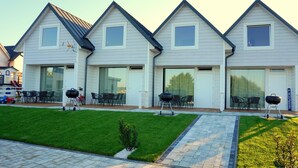 A modern house with a well-maintained lawn, outdoor seating, and barbecue grills. - Cottages for families with children or guests who want to relax. (Sarbinowo)